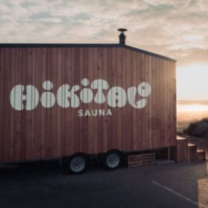 The wood fired sauna, Hikitalo, on the beach. The logo is painted on the outside in big white letters