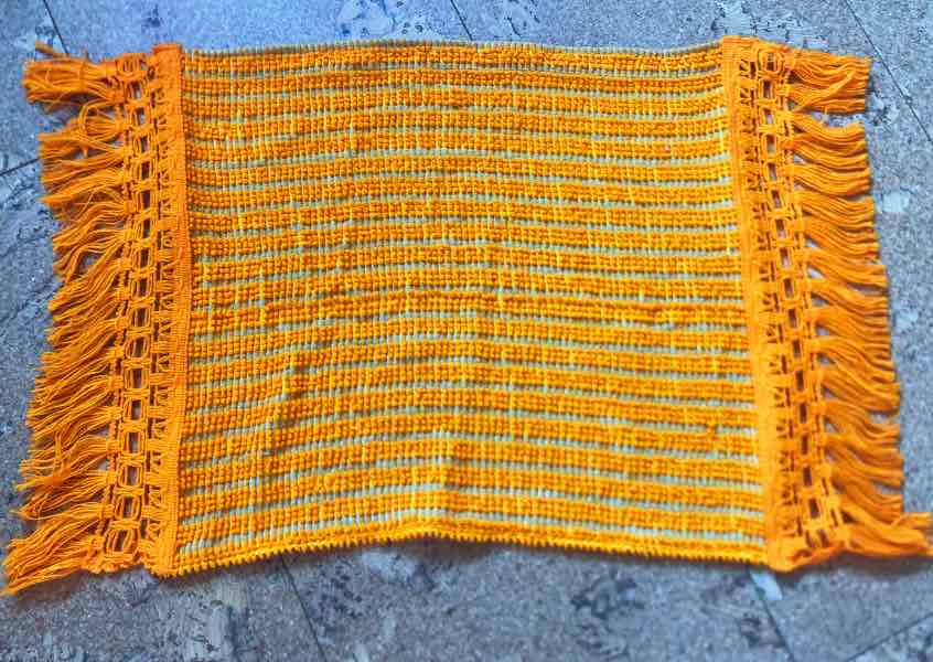 An orange sauna seat towel with vintage fringing for a retro look