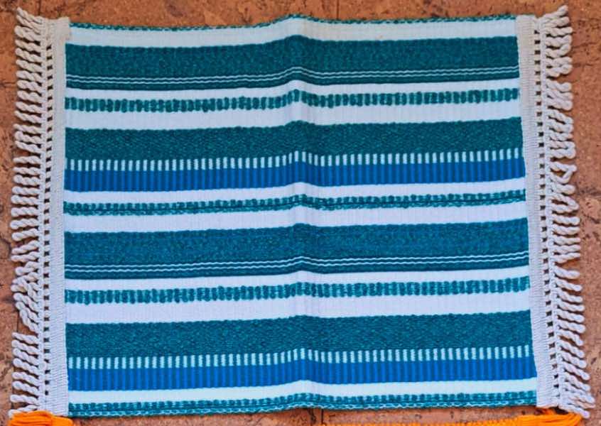 A blue, green & white striped sauna seat mat made from vintage bedspreads and finished with a fringing